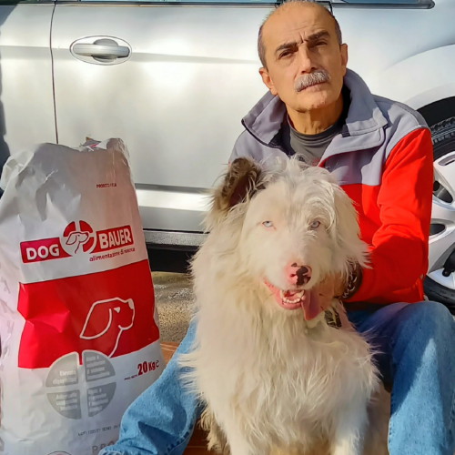 Uomo con i baffi che presenta il suo cane di nome Pepe e le crocchette Dogbauer
